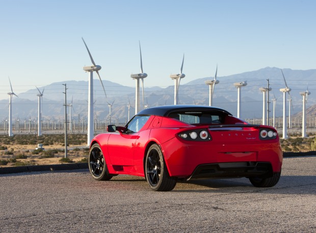 L'arrière d'une Tesla Roadster rouge devant des éoliennes